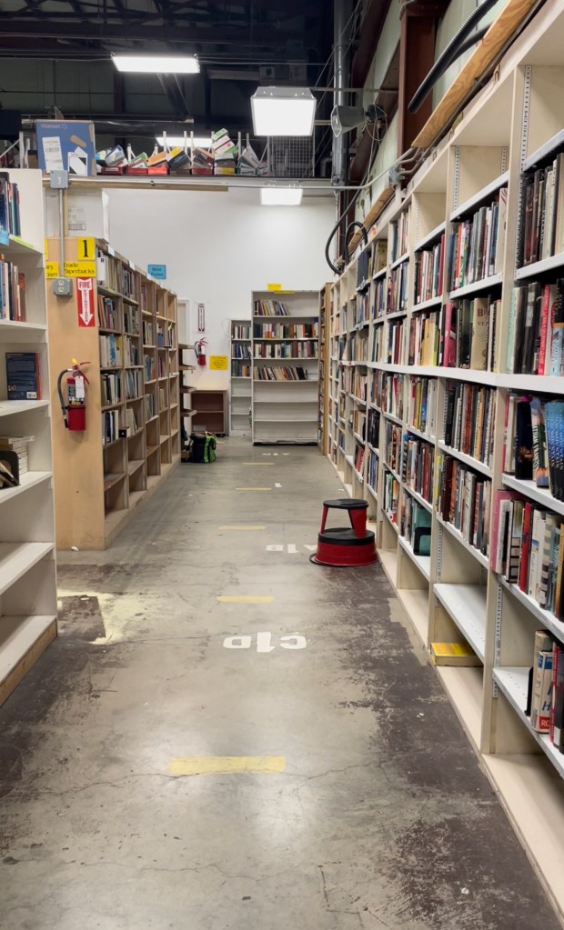 A photo of a long aisle of books in a warehouse. 